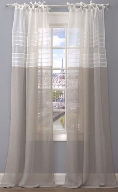 a window with sheer curtains in front of a cityscape