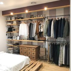 an organized bedroom with clothes hanging on shelves and wooden pallets in front of the bed