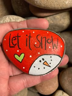 a hand holding a painted rock that says let it snow