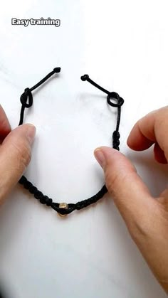 two hands are holding a string bracelet