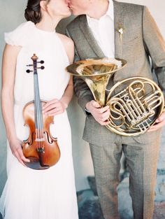 a man and woman kissing while holding musical instruments