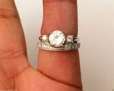 a woman's hand holding a ring with an oval shaped diamond in the middle