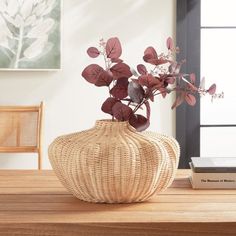 a wicker vase with red flowers in it on a table next to a book