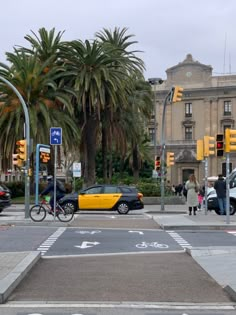 a yellow car is driving down the street in front of some buildings and palm trees