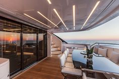 a dining area on the back of a boat with glass doors leading out to the ocean