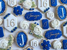 cookies decorated with royal blue and white icing are arranged on a table for a wedding