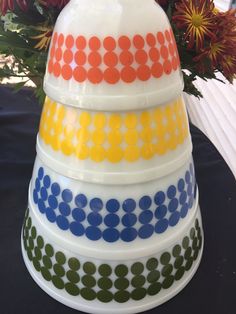 a multicolored stack of bowls sitting on top of a table next to flowers