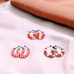 Show your team spirit and represent your game day team colors with these stunning orange and white heishi bead stainless steel hoop earrings.  - Available in 3 sizes: 1", 1.5" and 1.75" - Three unique designs to choose from Make a statement and cheer on your team in style with these trendy earrings. Perfect for game day or any occasion. Grab a pair now and show your support! Orange Small Hoop Earrings For Gift, Small Hoop Earrings Orange For Gift, Small Hoop Earrings Orange Gift, Small Hoop Earrings In Orange For Gifts, Clay Bead Earrings, Beaufort Nc, Spirit Game, Bead Hoop Earrings, Team Mom