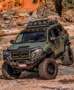 a green four - doored off road vehicle driving on rocks