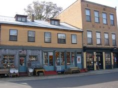 an old fashioned store front on the corner of a street with two buildings in the background