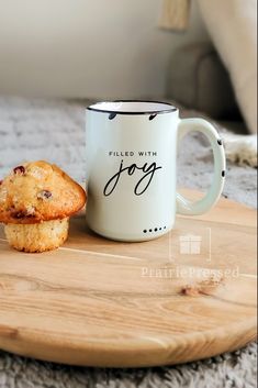 a muffin sitting next to a coffee cup on top of a wooden tray