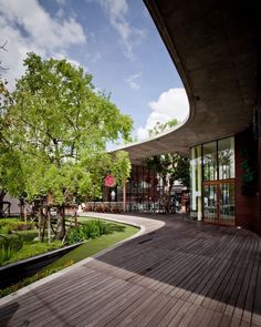 an empty wooden deck in front of a building with trees and grass on the ground