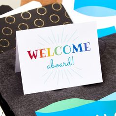 a welcome card sitting on top of a pile of folded paper with the words welcome aboard