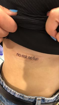 a woman with a tattoo on her stomach saying, no risk no fun in front of her