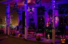 purple lights decorate the porch of a house with pumpkins and jack - o'- lanterns