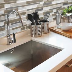 a kitchen sink with utensils and a cutting board on the counter next to it