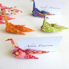 four origami cranes are on a table with a name card and place cards