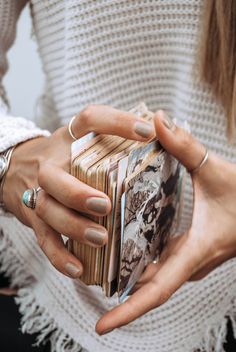 a woman is holding an open book in her hands while wearing rings and bracelets