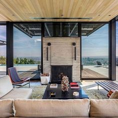 a living room with couches, tables and large windows looking out onto the city