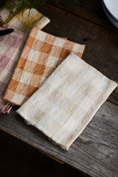 three napkins sitting on top of a wooden table next to a knife and fork