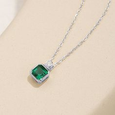 This exquisite pendant necklace showcases a brilliant emerald in a classic solitaire setting, radiating a lush green hue. Its elegant simplicity makes it a standout piece, perfect for enhancing any neckline with a touch of refined sophistication. Classic Green Emerald Necklace With Bezel Setting, Elegant Emerald Pendant Necklace With Clavicle Chain, Emerald Necklace In Brilliant Cut, Elegant Green Emerald Necklace With Brilliant Cut, Green Brilliant Cut Necklace For May Birthstone, Elegant Emerald Necklace For May Birthstone, Elegant Emerald Pendant Necklace With Bezel Setting, Fine Jewelry Green Emerald Necklace With Brilliant Cut, Fine Jewelry Emerald Necklace With Brilliant Cut