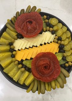 a platter with grapes, pickles, cheese and sausages arranged in the shape of an eye