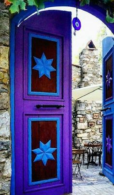 an open purple door with stars painted on the doors and side panels, in front of a stone wall