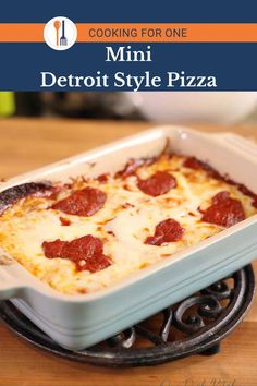 a close up of a pizza in a pan on a stove with the title cooking for one mini detroit style pizza