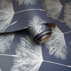 a wallpaper with white feathers on it and blue paper in the background that is rolled up