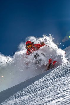 a man riding a snowboard down the side of a snow covered slope on a sunny day