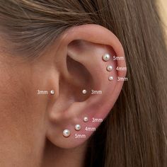 a woman's ear with three different types of pearls on the side of her ear