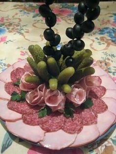 a cake decorated with flowers and fruits on top of a tablecloth covered table cloth