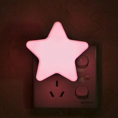 a pink star shaped light sitting on top of a wall