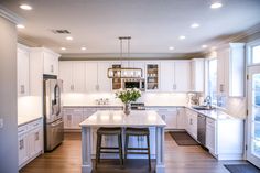 a kitchen with white cabinets and an island in the middle, surrounded by wood floors