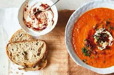 a bowl of tomato soup with bread on the side