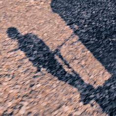 the shadow of two people walking down a dirt road