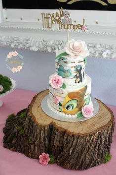 a three tiered cake sitting on top of a tree stump