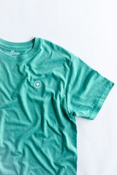 Feel the ultimate blend of comfort and style with The Juan and Only Signature Tee in Saltwater. This men’s signature tee features a super soft vintage wash, designed to become your go-to shirt for any casual occasion. Crafted from a high-quality blend of 52% polyester and 48% ringspun cotton, this 5.7oz cotton blend t-shirt offers a lightweight yet durable feel. The subtle saltwater color, paired with the signature Palmr Palm Tree logo, brings a touch of elegance to your everyday style. Slip int Acid Wash Organic Cotton Crew Neck Top, Casual Washed T-shirt For Loungewear, Washed Crew Neck T-shirt For Loungewear, Green Washed Crew Neck Top, Green Washed Casual T-shirt, Casual Green Washed T-shirt, Summer Loungewear Washed T-shirt, Sporty Washed T-shirt For Summer, Sporty Washed Relaxed Fit T-shirt