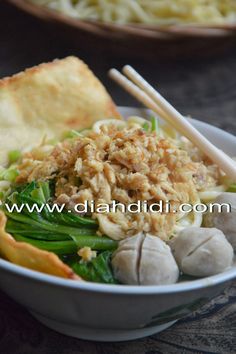 a bowl filled with noodles and vegetables next to chopsticks on top of a table