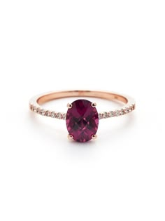 a pink tourmaline ring with diamonds on the band and an oval cut stone in the center