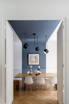 a dining room with blue walls and white chairs