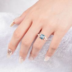 a woman's hand wearing a ring with an aqua blue topazte and diamond accents