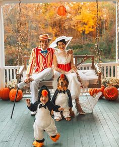 a family dressed up for halloween sitting on a porch swing with their dog and cat costumes