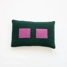 a green pillow with two pink squares on the front and one in the back, against a white background