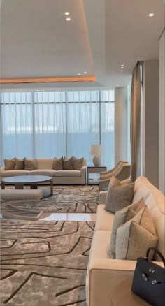 a living room filled with lots of furniture next to a tall glass window covered in curtains