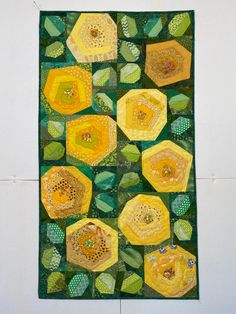 a quilted wall hanging with yellow and green flowers