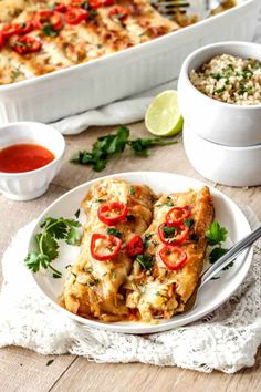 a white plate topped with chicken enchiladas next to a casserole dish