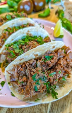 three tacos with meat and herbs on a plate