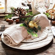 the table is set for christmas dinner with silverware and napkins, pine cones