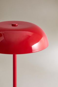 a red table lamp sitting on top of a white floor